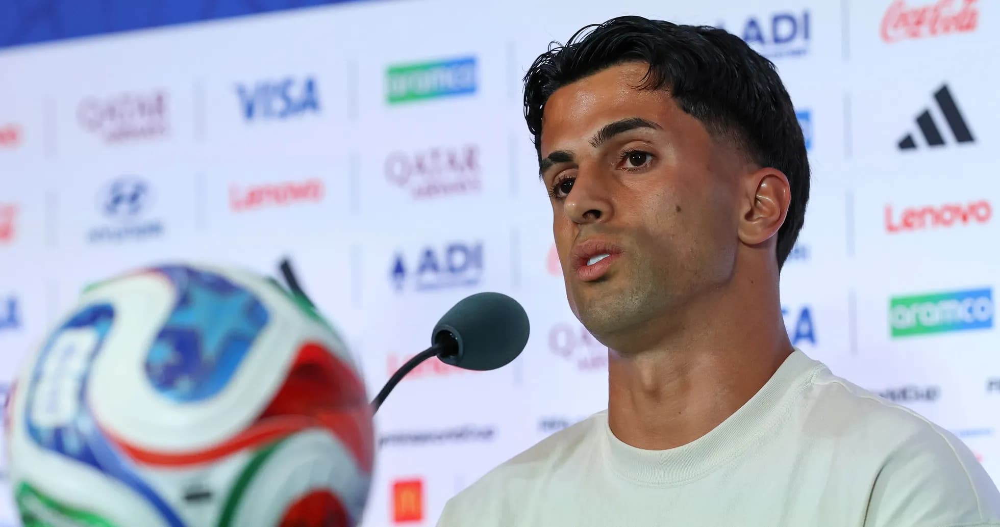 Player speaking at press conference with football in view