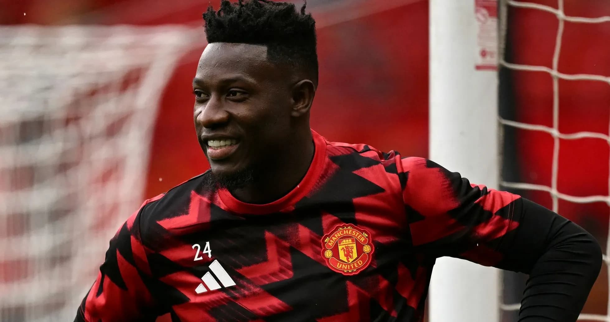 Goalkeeper in Manchester United kit smiling on pitch Goalkeeper in Manchester United kit smiling on pitch