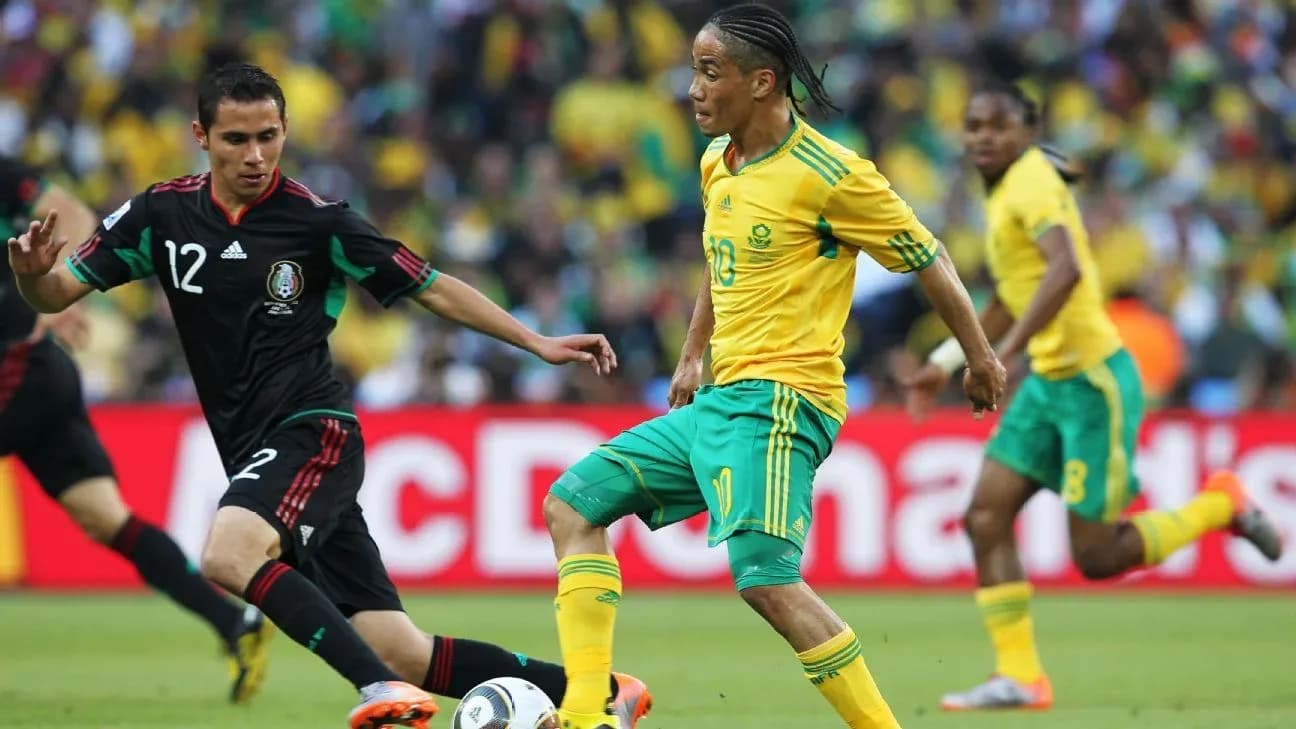 South African player dribbling past Mexican defender South African player dribbling past Mexican defender