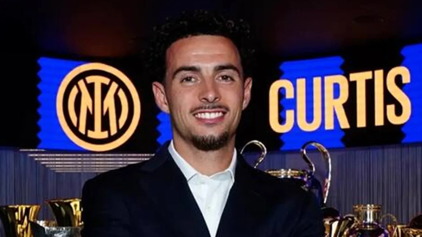 Player smiling with trophies and club logo backdrop Player smiling with trophies and club logo backdrop