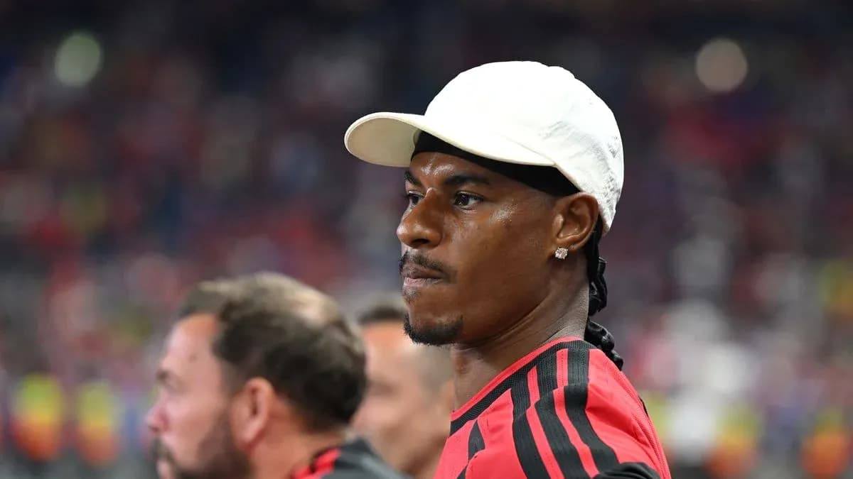 Player in red jersey observing from sidelines Player in red jersey observing from sidelines