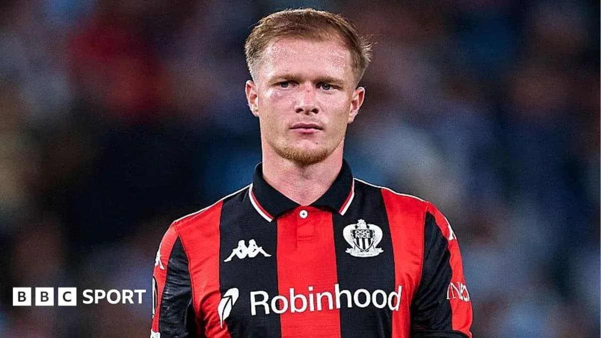 Player in black and red jersey on field Player in black and red jersey on field
