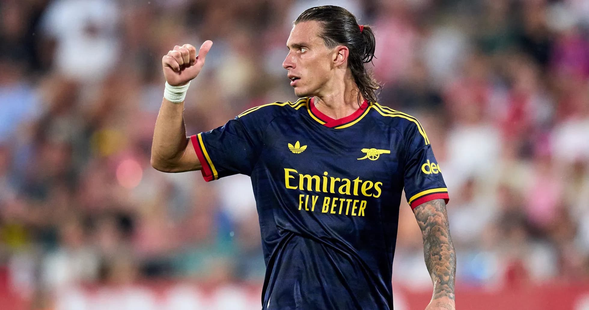 Player in Arsenal kit giving thumbs up on field Player in Arsenal kit giving thumbs up on field