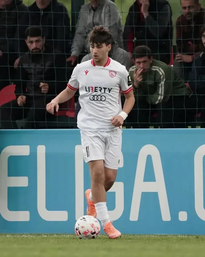 Player in white jersey dribbling ball on field Player in white jersey dribbling ball on field