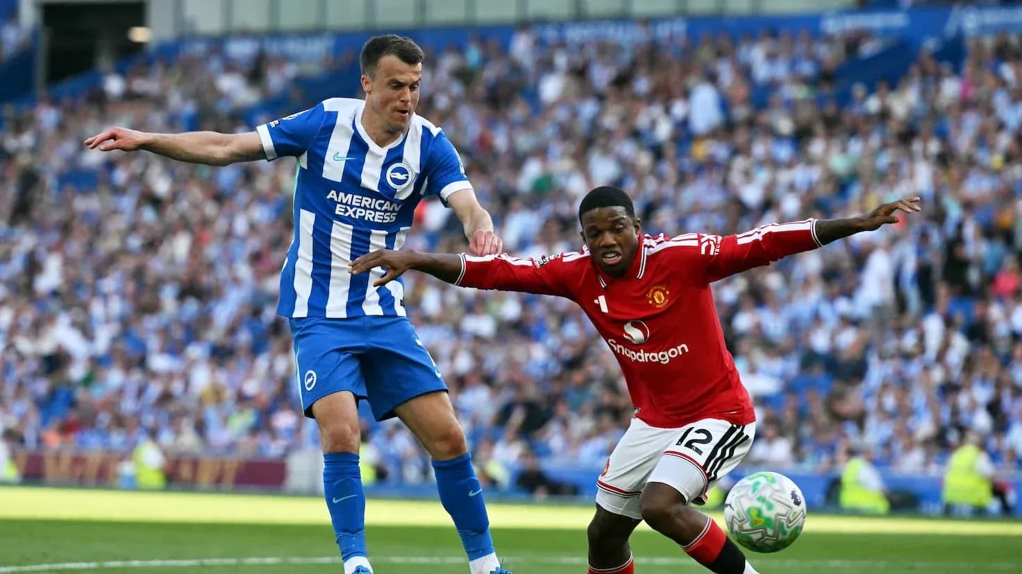 Brighton player challenging Manchester United opponent Brighton player challenging Manchester United opponent