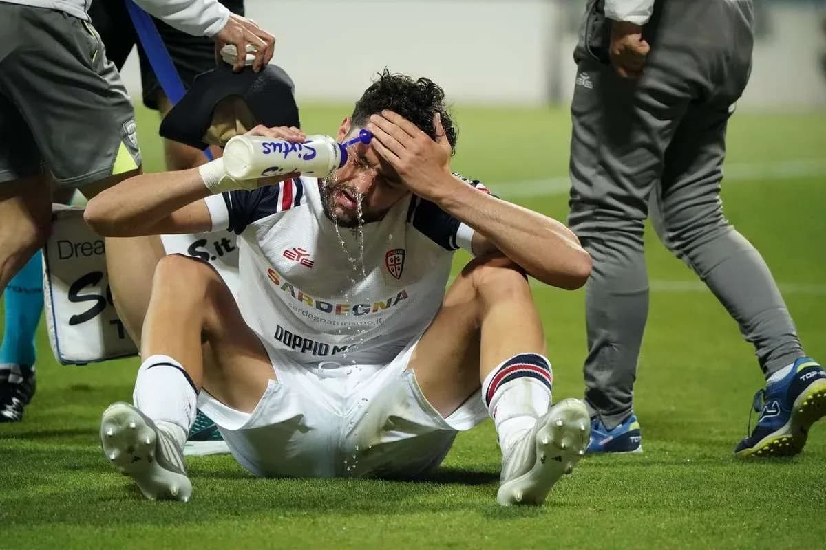 Player sitting on field pouring water on face Player sitting on field pouring water on face