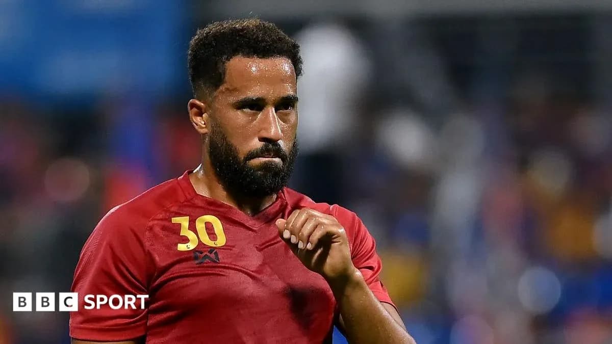 Player in red jersey during match, focused expression Player in red jersey during match, focused expression
