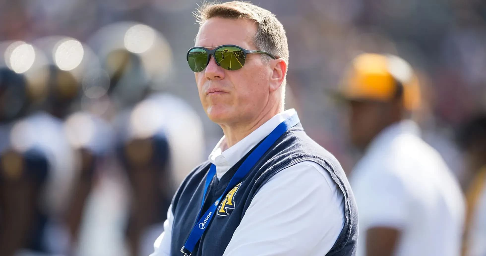 Man wearing sunglasses observing a football game Man wearing sunglasses observing a football game