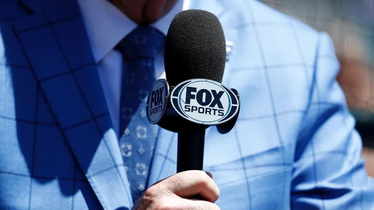 Person holding FOX Sports microphone in blue suit Person holding FOX Sports microphone in blue suit
