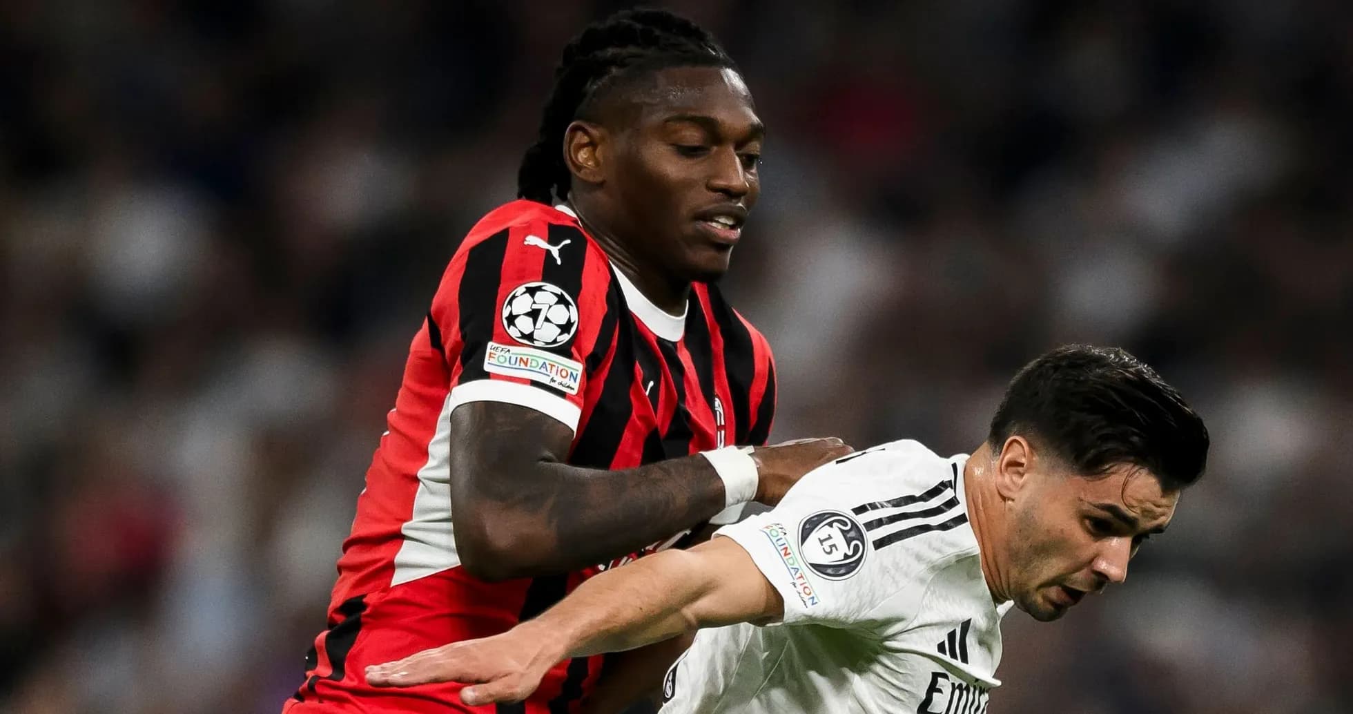 Player in red and black tackling opponent in white Player in red and black tackling opponent in white