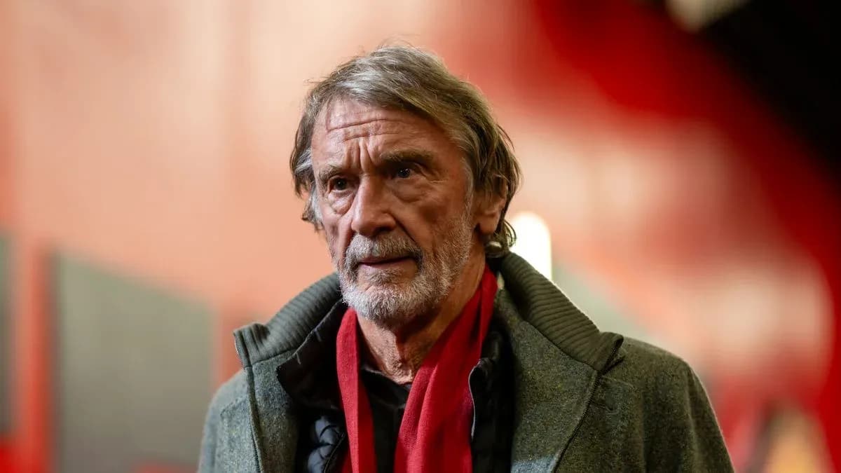 Man wearing a gray coat and red scarf indoors Man wearing a gray coat and red scarf indoors