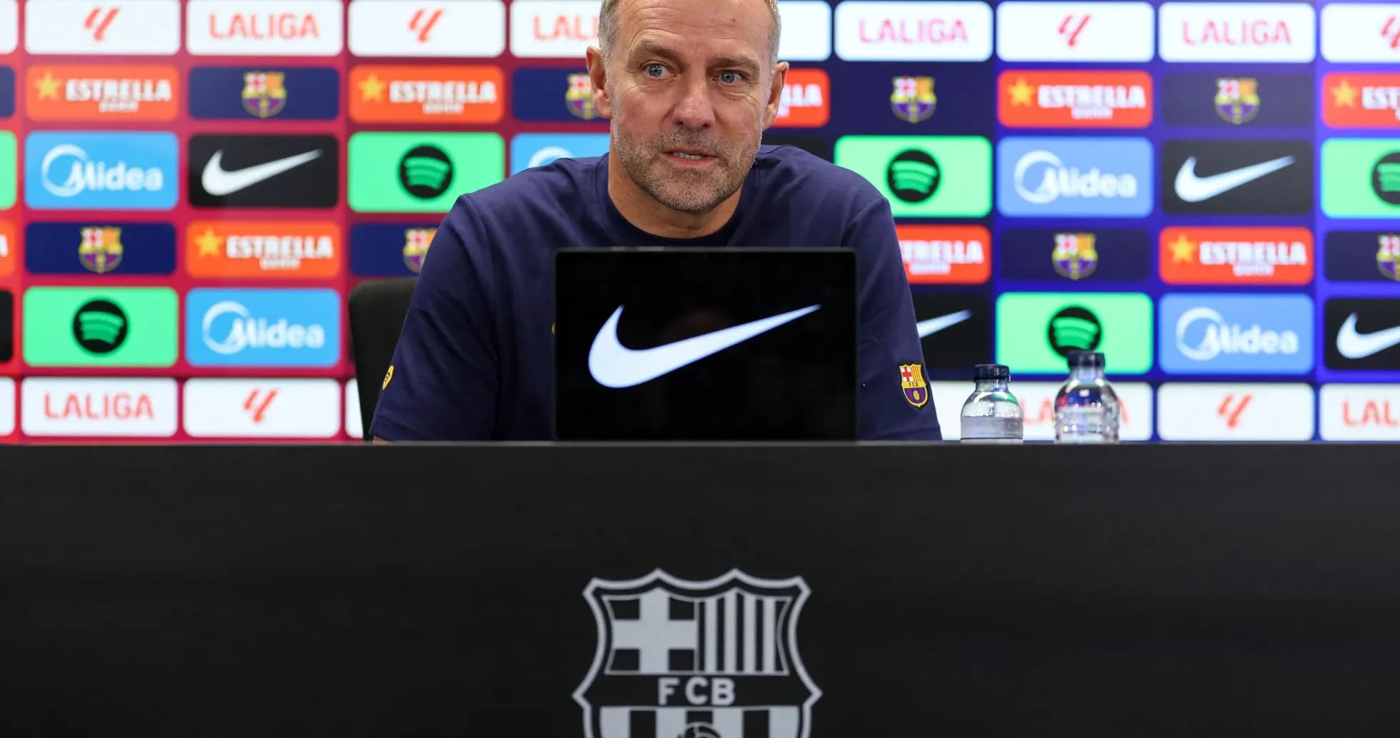 Manager speaking at press conference with team logos Manager speaking at press conference with team logos