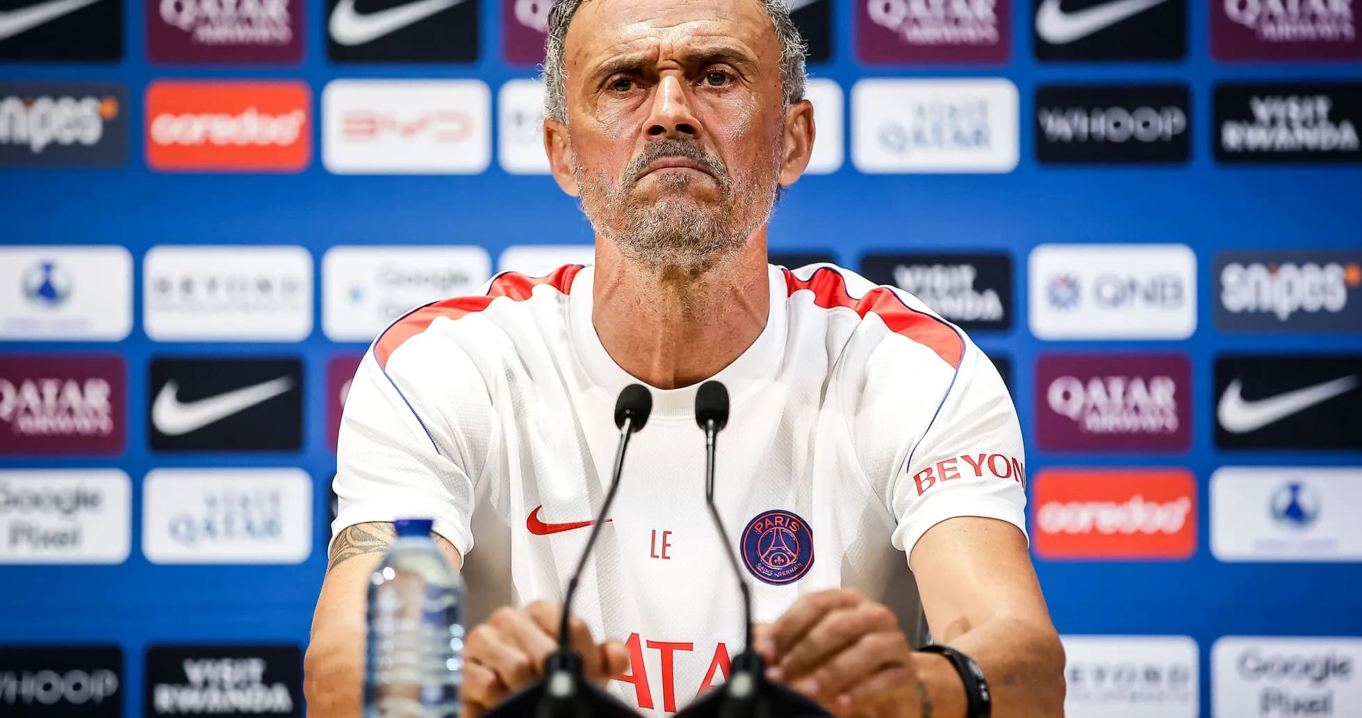 Manager at press conference with team branding behind Manager at press conference with team branding behind