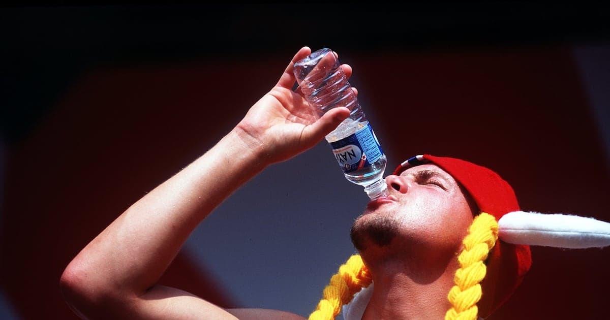 Person drinking water during outdoor event Person drinking water during outdoor event