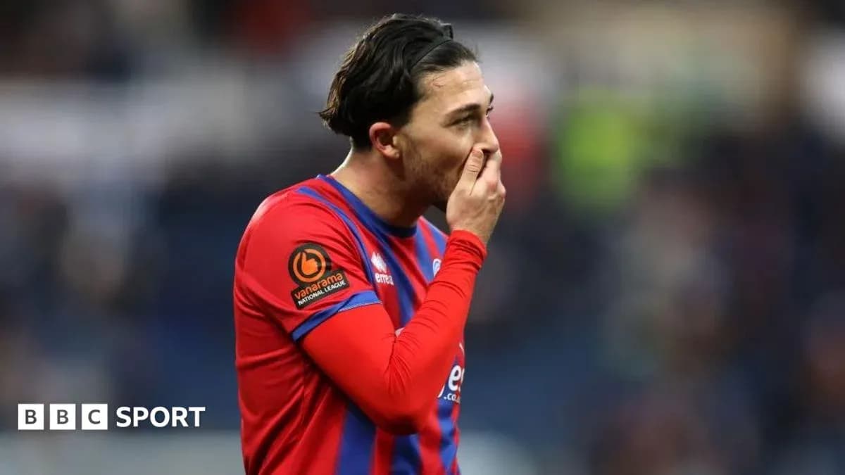 Player in red and blue kit touching face during match Player in red and blue kit touching face during match