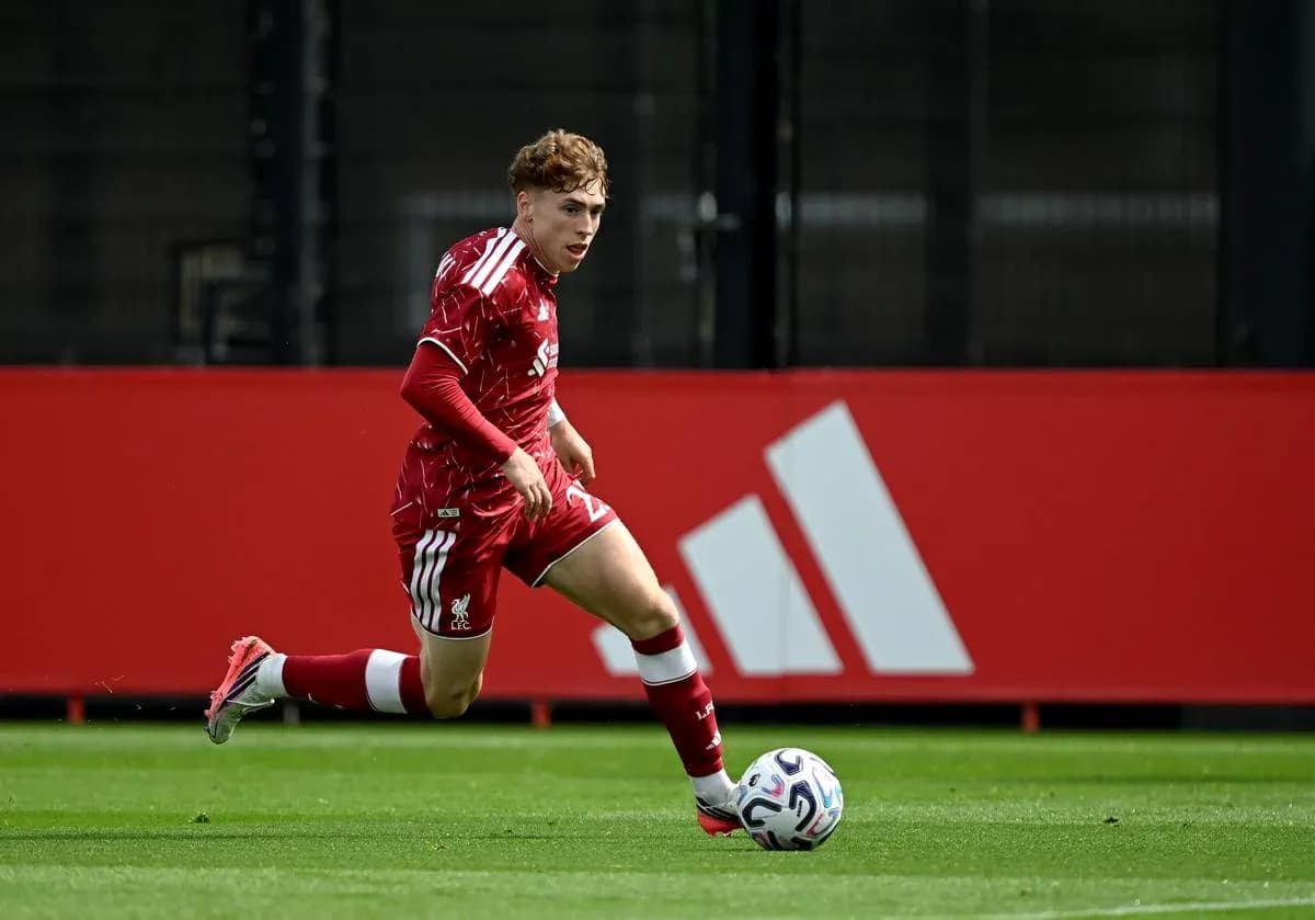 Player in red kit sprinting towards soccer ball Player in red kit sprinting towards soccer ball