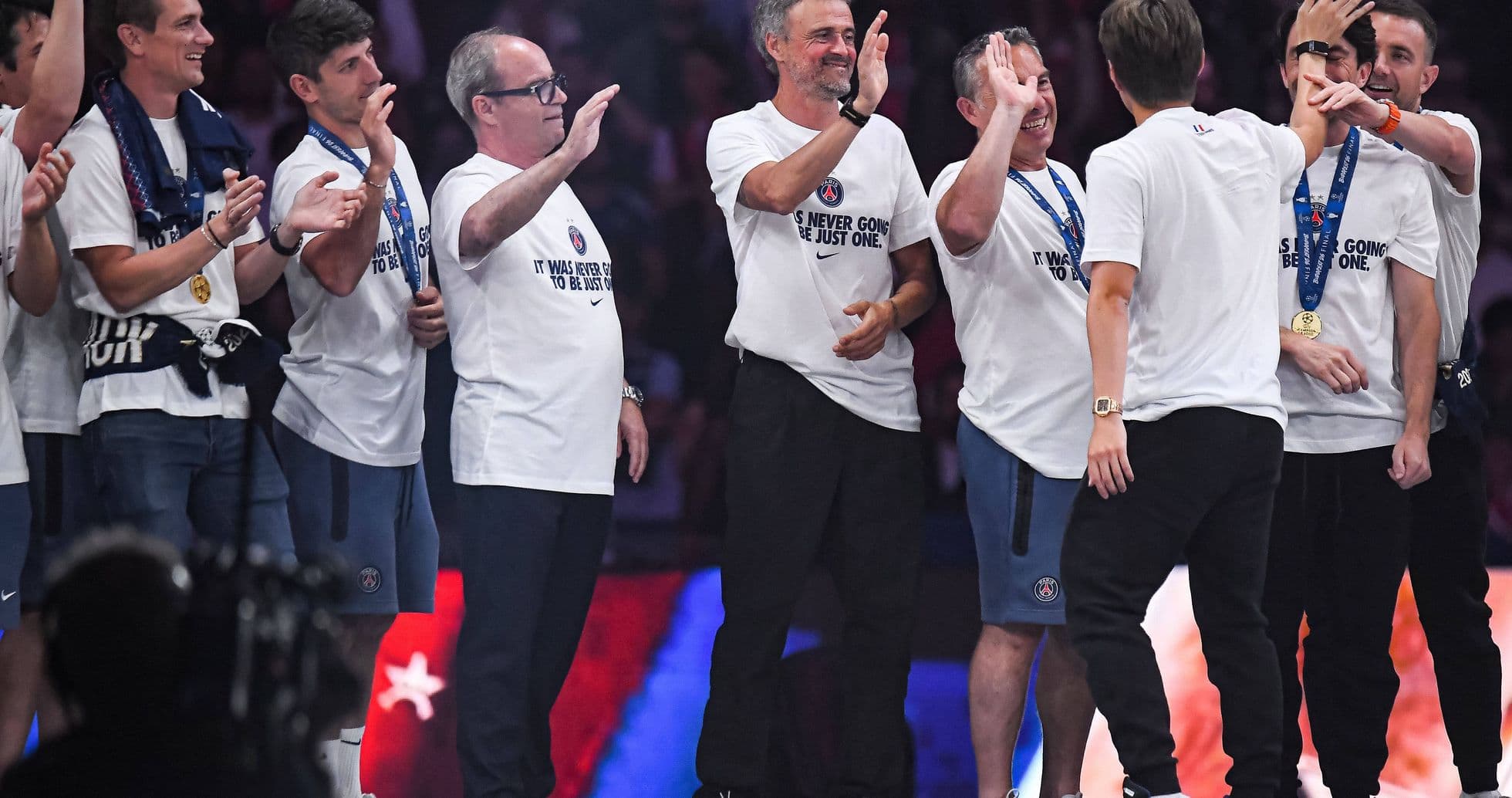 Team celebrating with medals and T-shirts on stage Team celebrating with medals and T-shirts on stage
