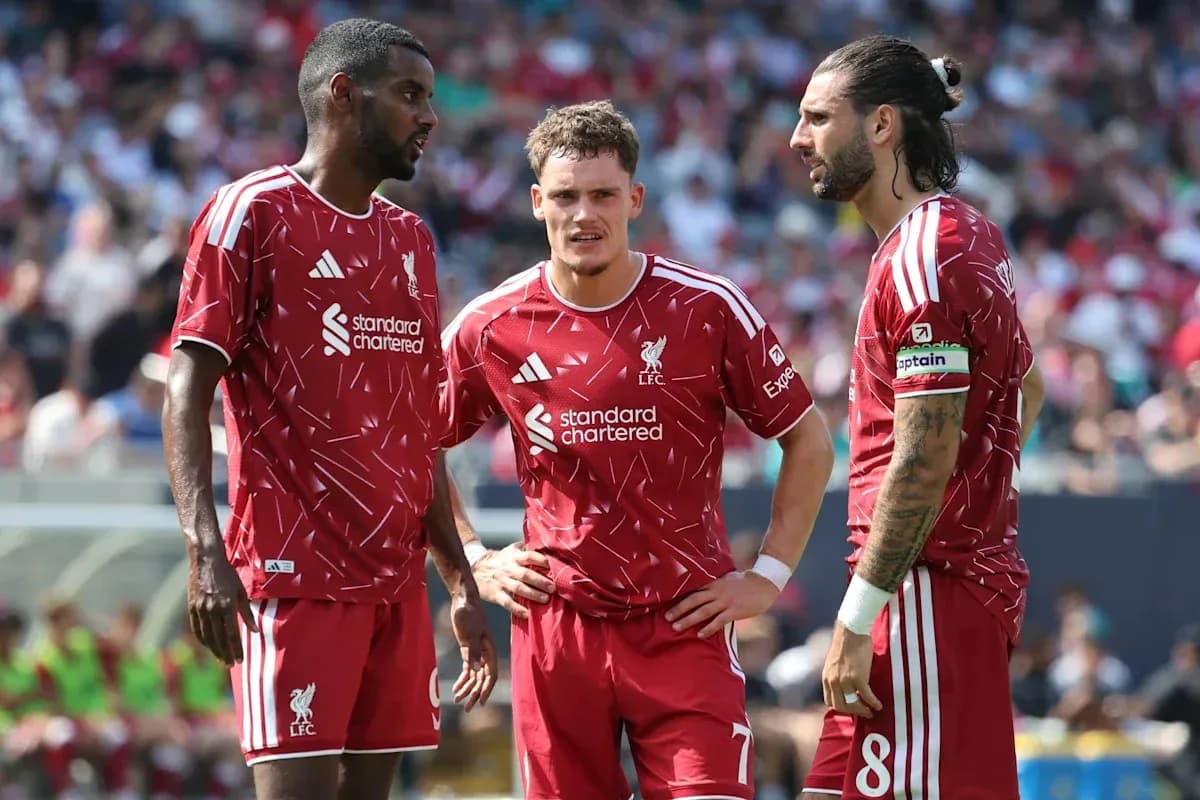 Three Liverpool players discussing on the field Three Liverpool players discussing on the field