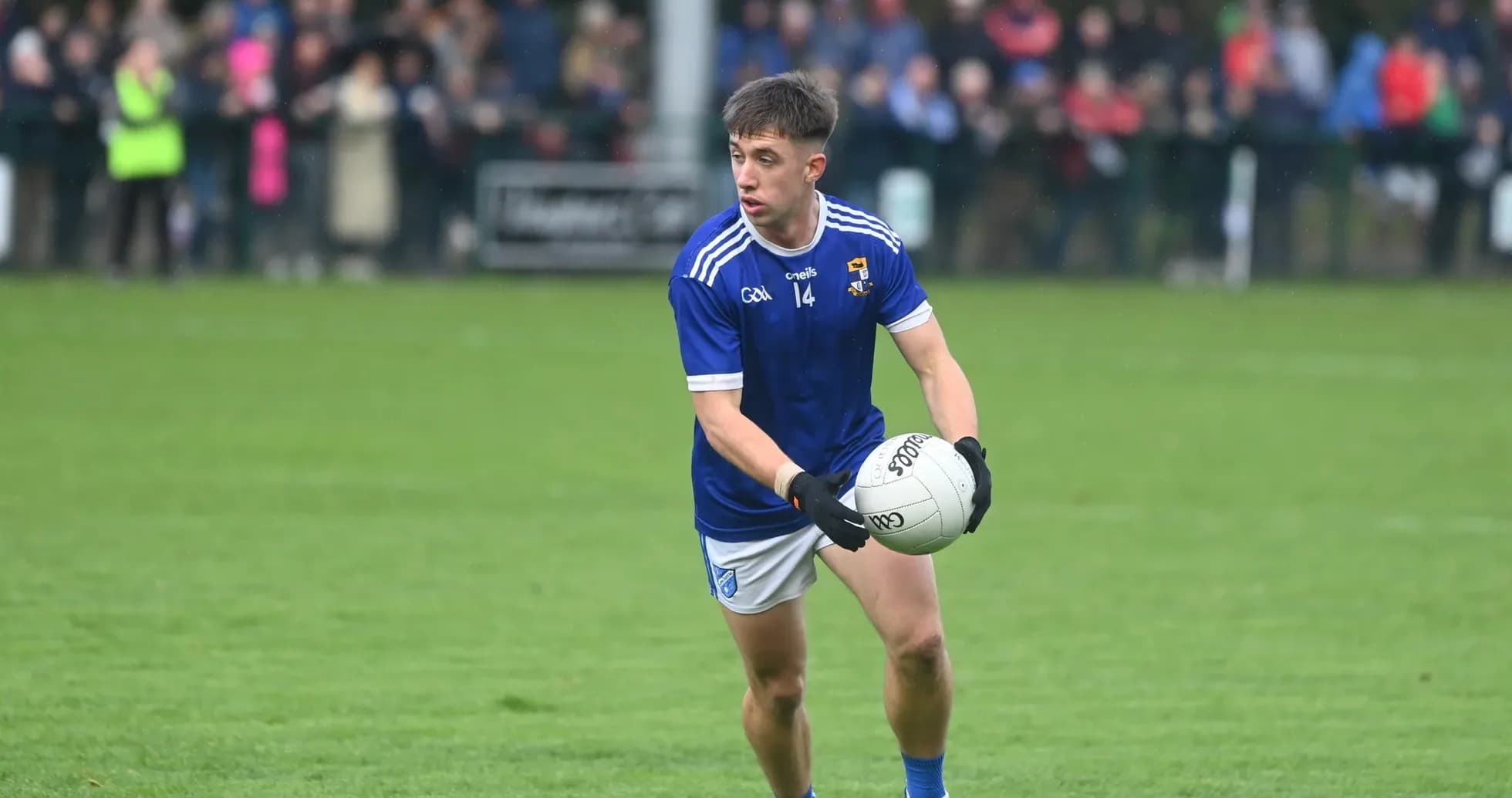 Player in blue jersey holding a football on field Player in blue jersey holding a football on field