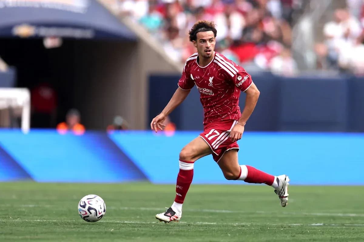 Player in red Liverpool kit dribbling ball on field Player in red Liverpool kit dribbling ball on field