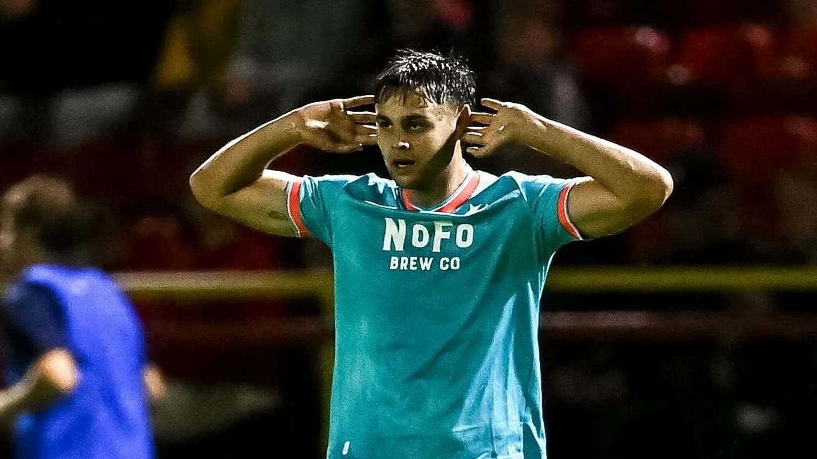 Player gesturing while wearing teal team jersey Player gesturing while wearing teal team jersey