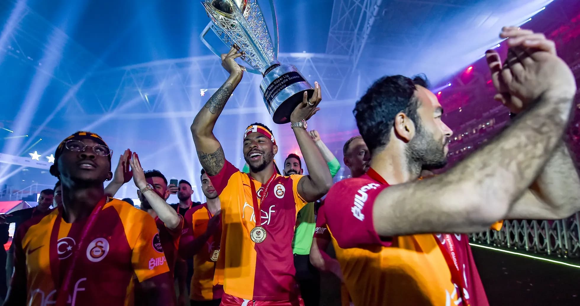 Player holding trophy with teammates celebrating Player holding trophy with teammates celebrating