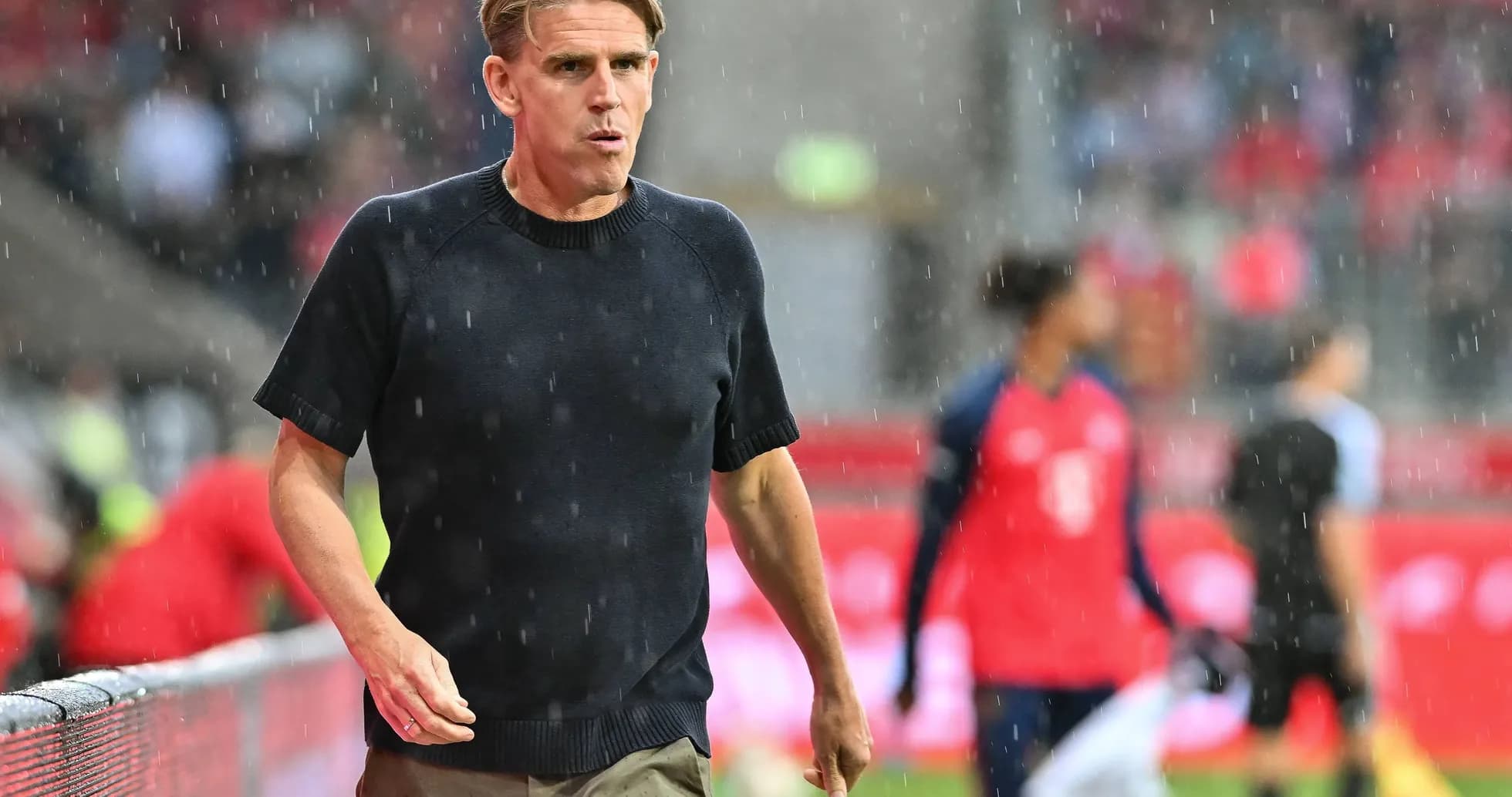 Coach walking on the sideline during rainy match Coach walking on the sideline during rainy match