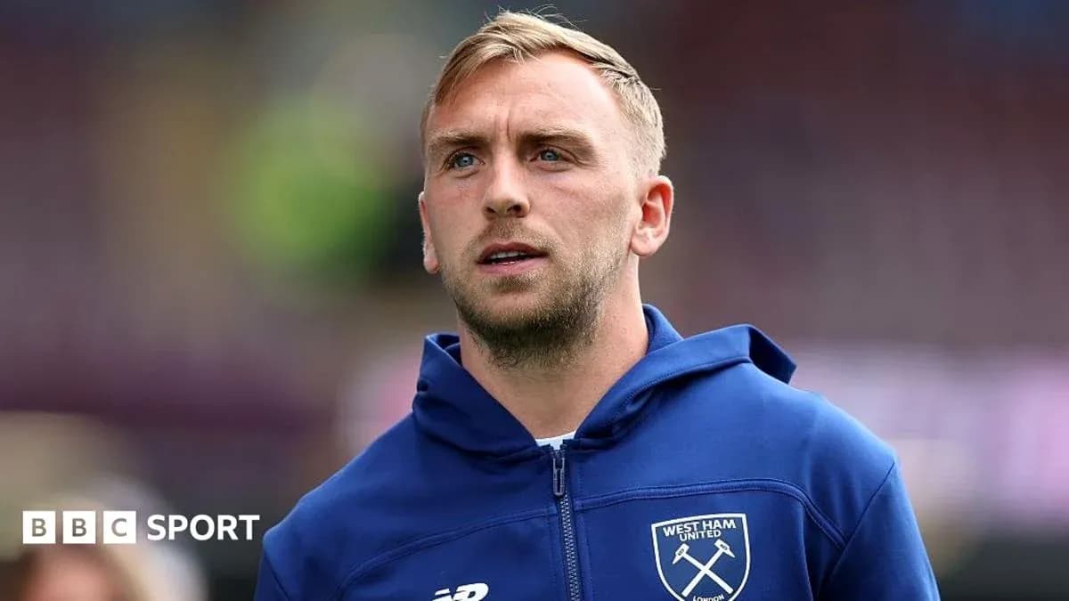Player in West Ham United hoodie on pitch Player in West Ham United hoodie on pitch
