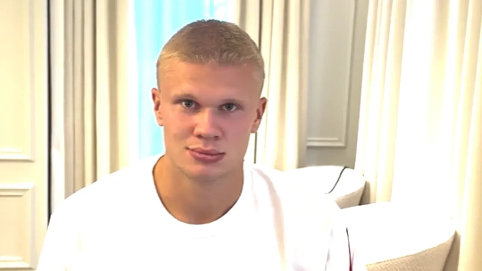 Young man sitting indoors in a white shirt Young man sitting indoors in a white shirt