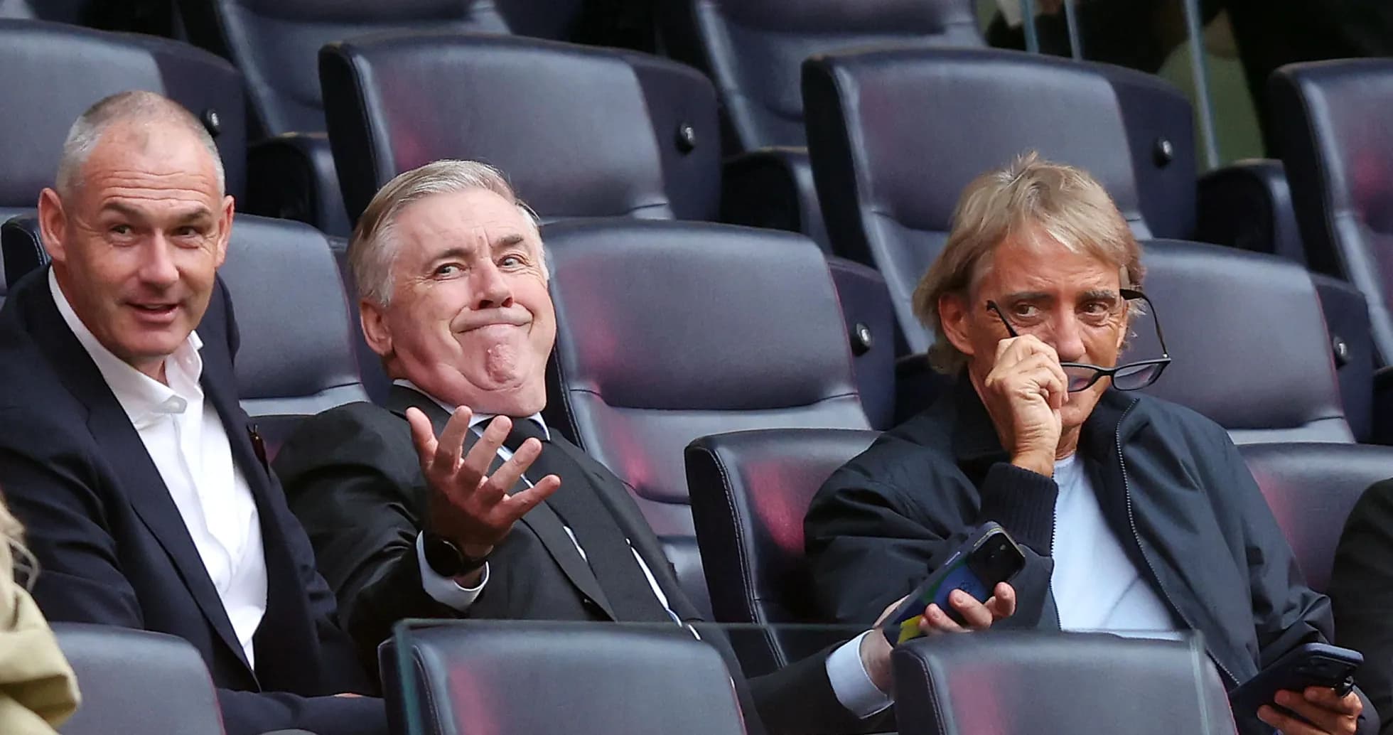 Three men seated in stadium, watching the match Three men seated in stadium, watching the match