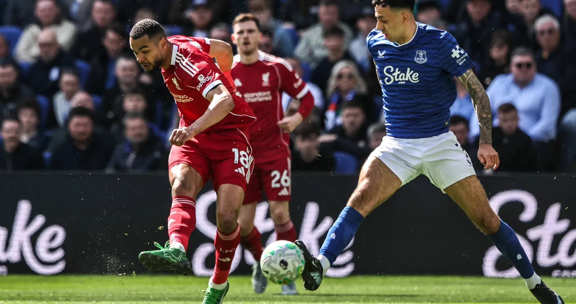 Liverpool player dribbling past Everton defender during match Liverpool player dribbling past Everton defender during match