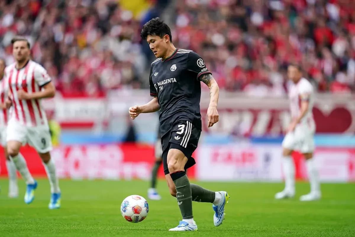 Player in black kit preparing to kick ball during match Player in black kit preparing to kick ball during match