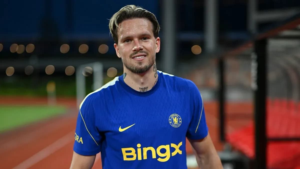 Player in blue Chelsea jersey smiling on field Player in blue Chelsea jersey smiling on field