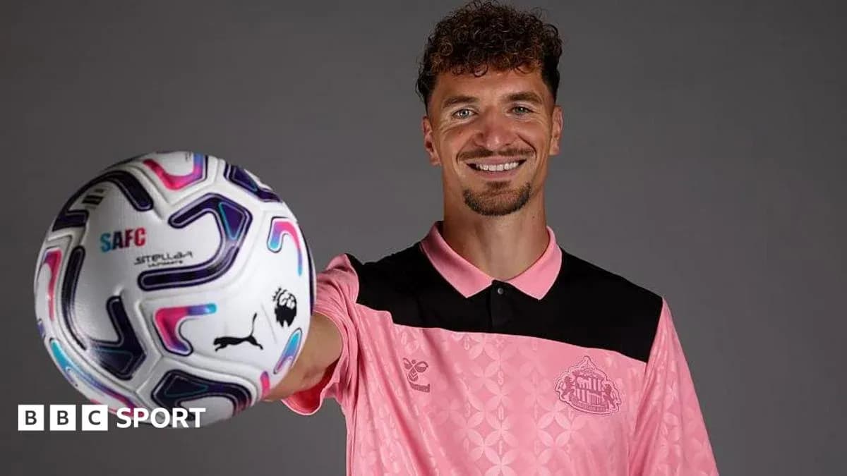 Player posing with football in pink kit Player posing with football in pink kit