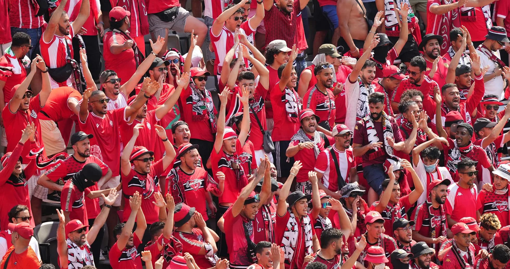 Fans celebrating in red attire during a match Fans celebrating in red attire during a match