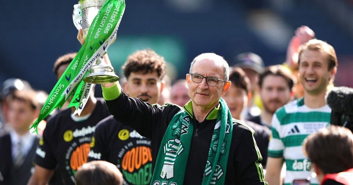 Manager holding trophy with team celebrating behind Manager holding trophy with team celebrating behind