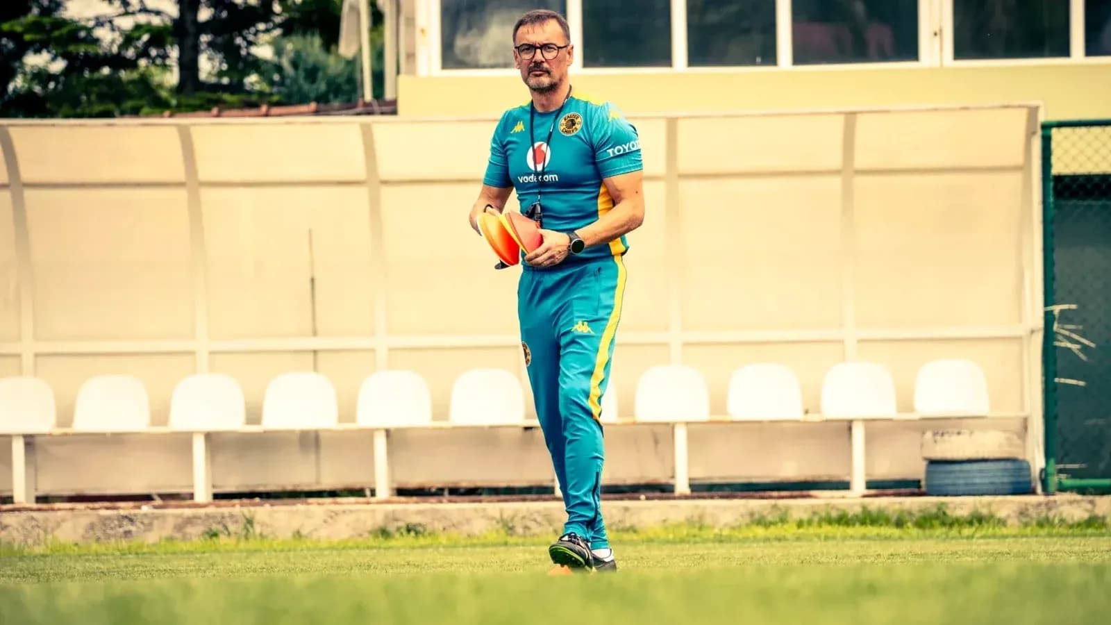 Coach walking on field holding training equipment Coach walking on field holding training equipment