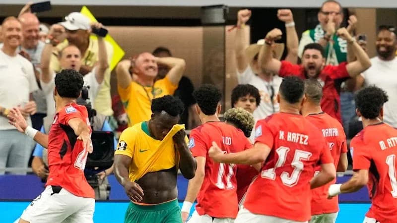 Players celebrating a goal with fans in background Players celebrating a goal with fans in background