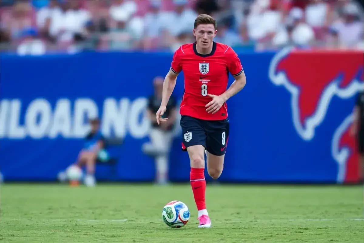 Player in red kit dribbling ball on field Player in red kit dribbling ball on field