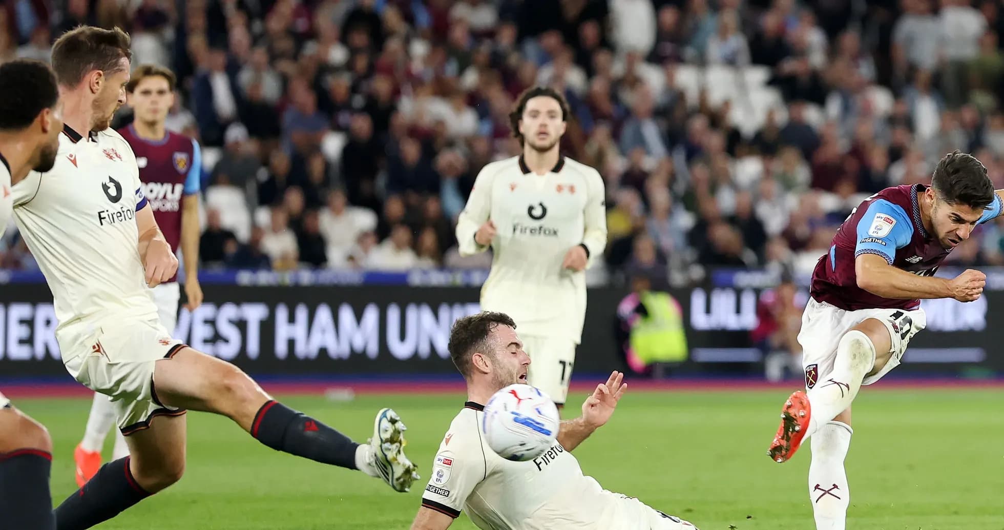 Player kicking ball during match, two players nearby Player kicking ball during match, two players nearby