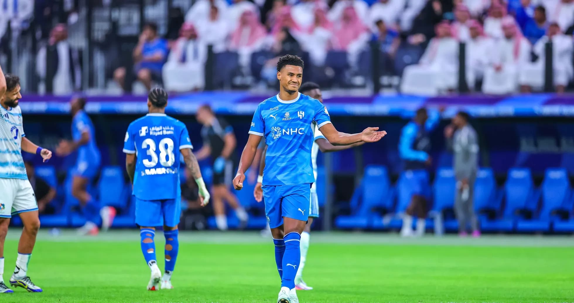 Player gesturing during match with teammates in background Player gesturing during match with teammates in background