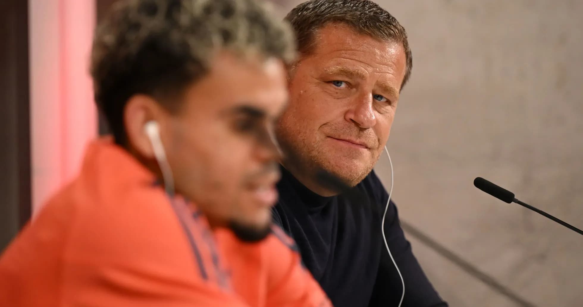 Two individuals at a press conference table Two individuals at a press conference table