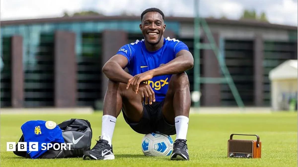 Player sitting on grass with football and bag Player sitting on grass with football and bag