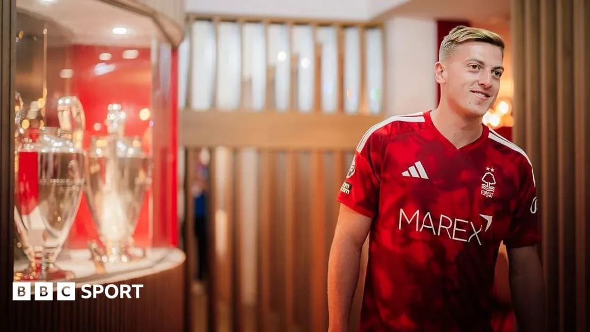 Player in Nottingham Forest jersey next to trophies Player in Nottingham Forest jersey next to trophies