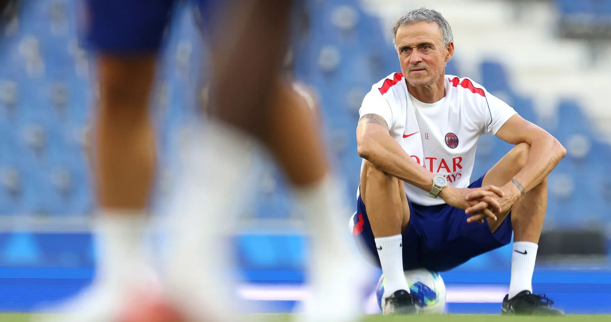 Coach squatting on the pitch during training session Coach squatting on the pitch during training session