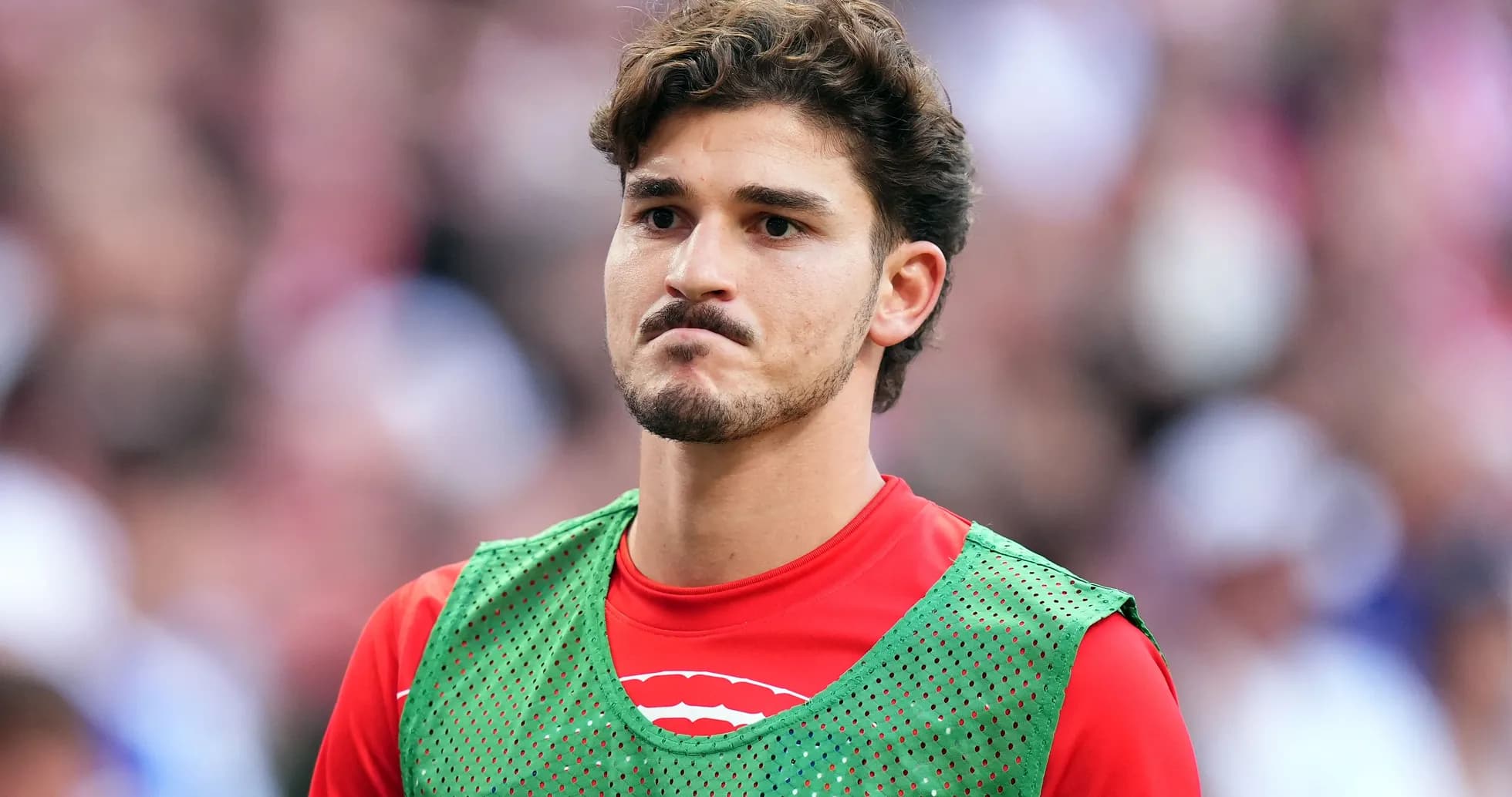 Player wearing training bib on sidelines during match Player wearing training bib on sidelines during match