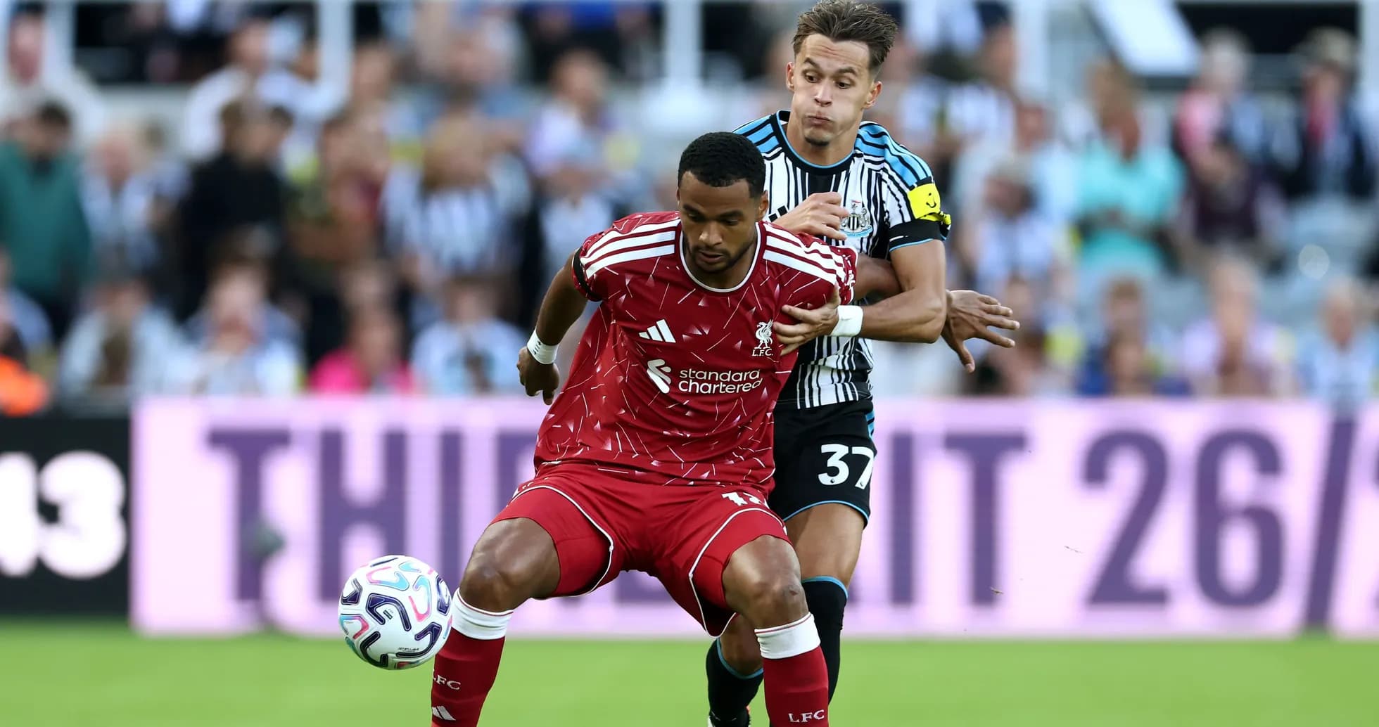 Player from Liverpool evading tackle by Newcastle defender Player from Liverpool evading tackle by Newcastle defender