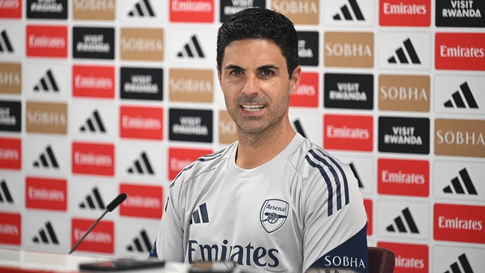 Manager speaking at press conference with Arsenal logo Manager speaking at press conference with Arsenal logo