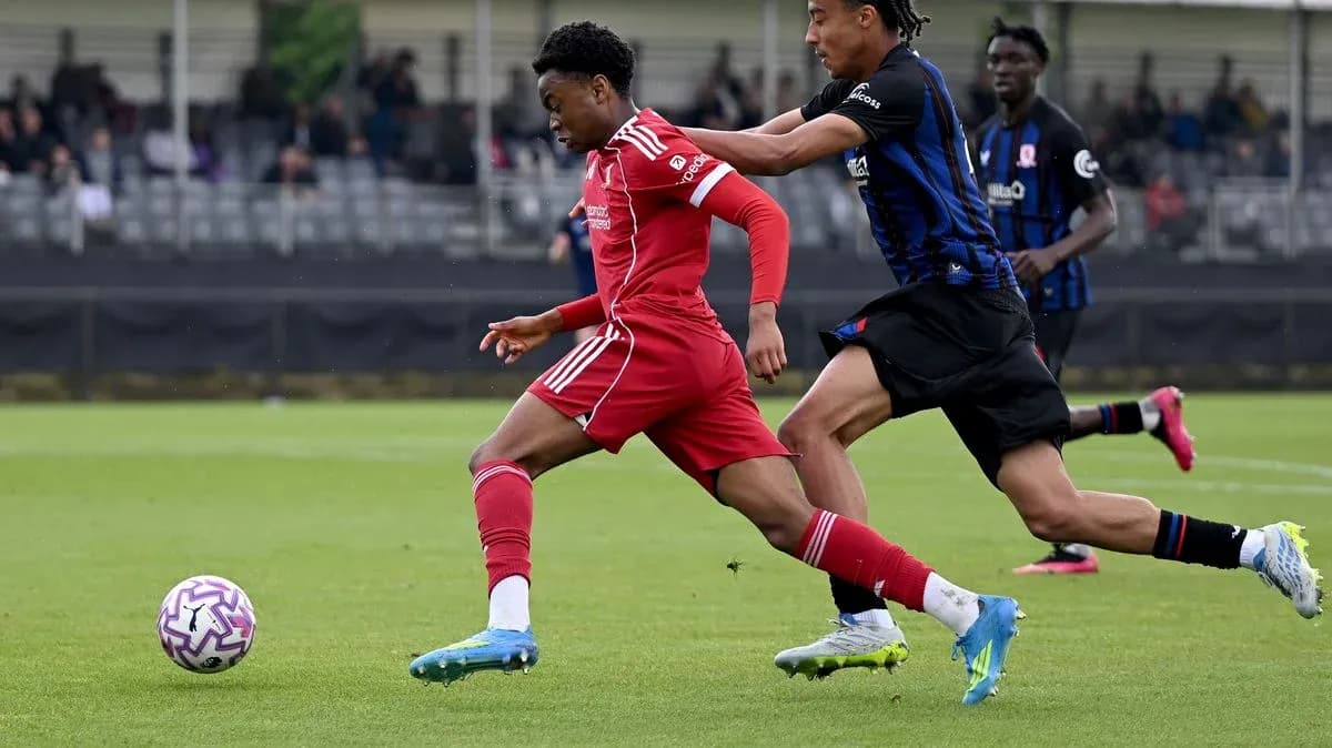 Player in red shirt dribbling past defender in blue Player in red shirt dribbling past defender in blue